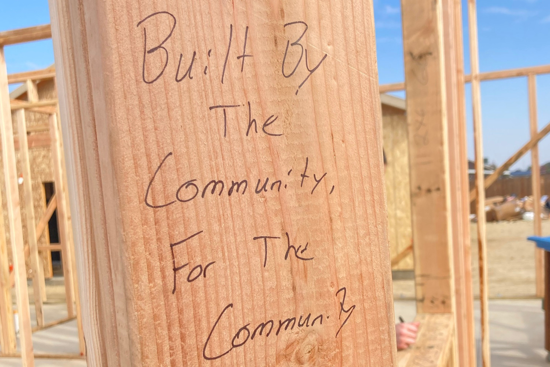 Wooden stud with "built by the community, for the community" written on it in marker