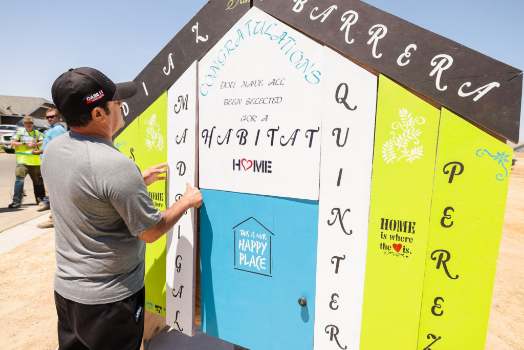 Man placing a wooden board on a wooden sign