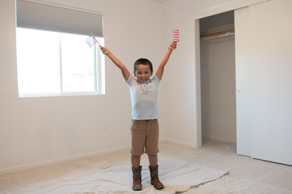 vet page (1) Little boy holding small flags and throwing his arms up